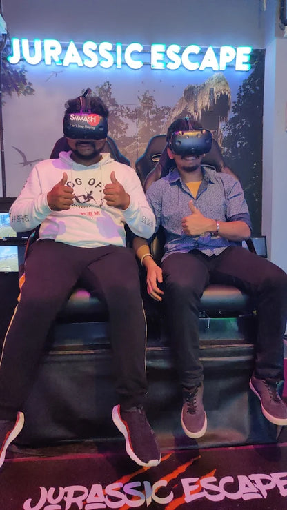 Two young men wearing VR headsets give thumbs up in a Jurassic Escape arcade.