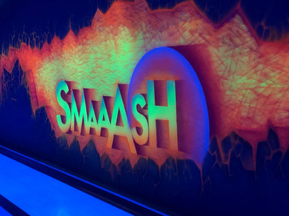 Neon sign for "SMAAASH" in a bowling alley with a fiery background.