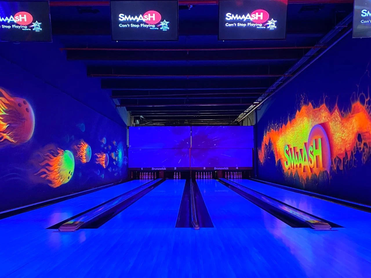 A neon-lit bowling alley with glowing jellyfish and fire graphics, featuring multiple lanes and screens.