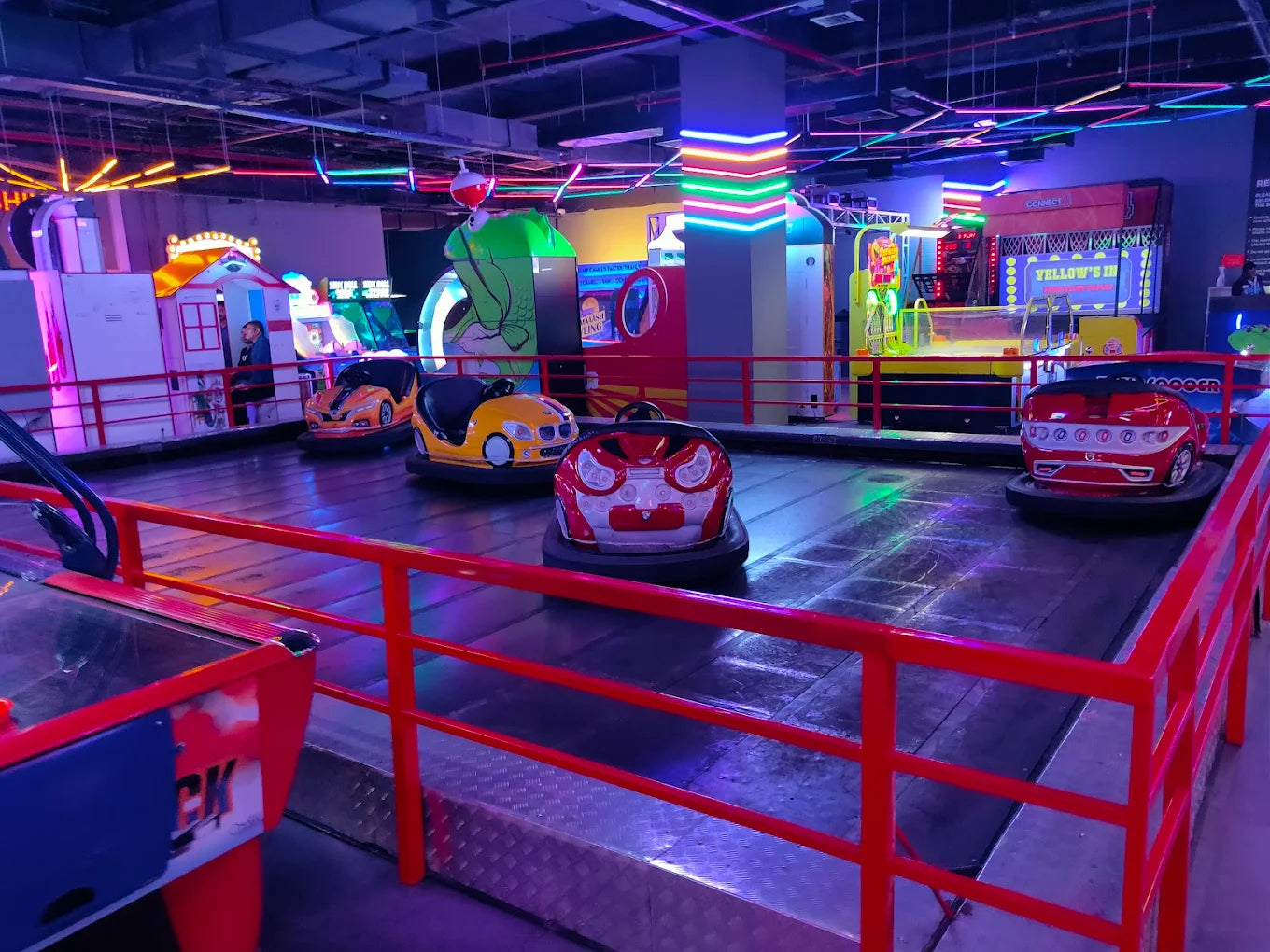 Bumper cars in an arcade, with colorful lights and game machines in the background.