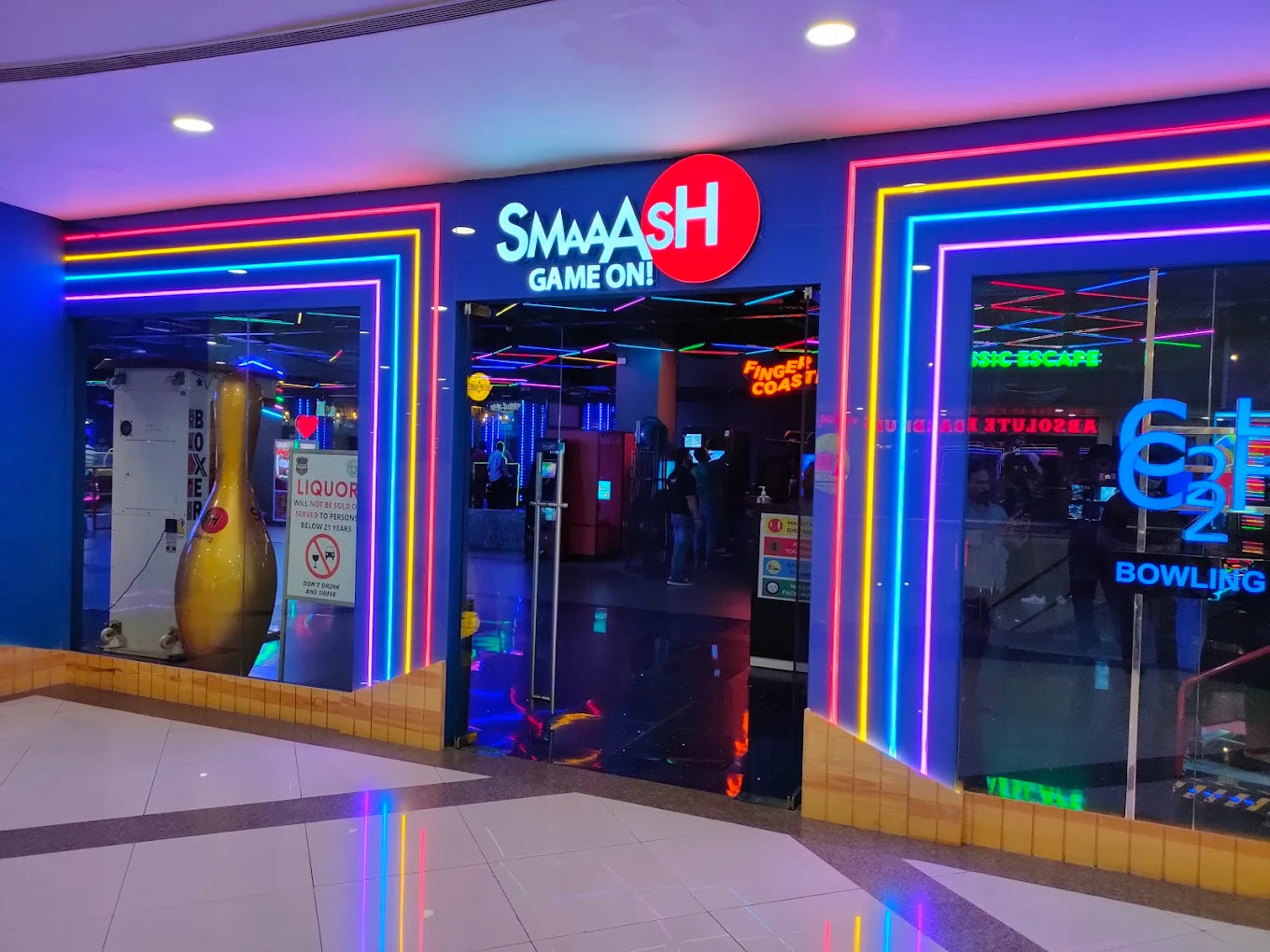 A brightly lit bowling alley entrance with neon lights and a large bowling pin statue.