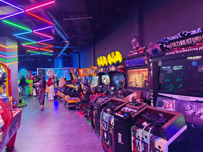 Arcade with neon lights and people playing games.