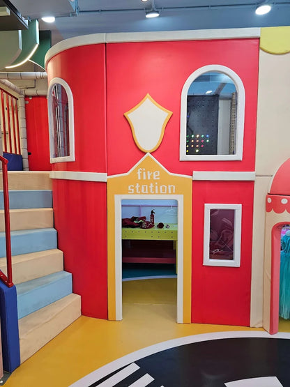 A colorful indoor playground designed as a fire station, with stairs and an open doorway.