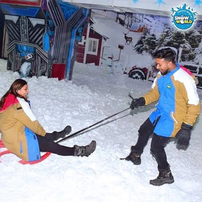 Young adults sledding in a snowy indoor park.