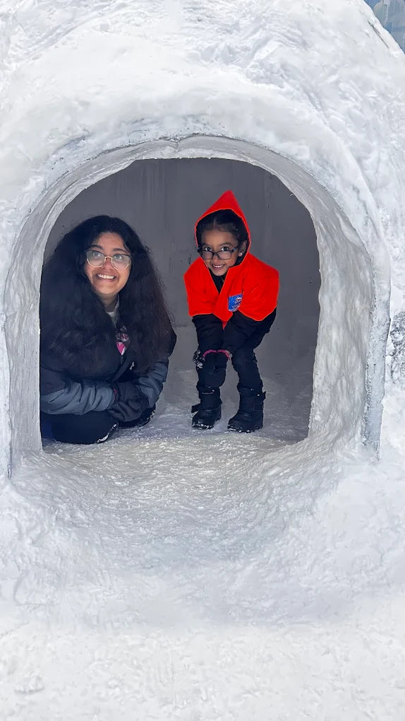 Two young girls smile from inside a snow cave.