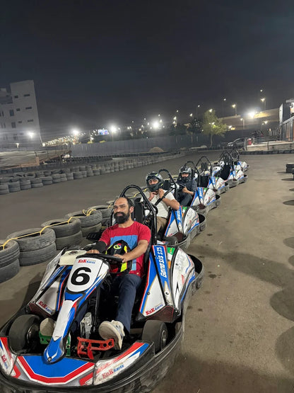 Adults in go-karts at a nighttime track.