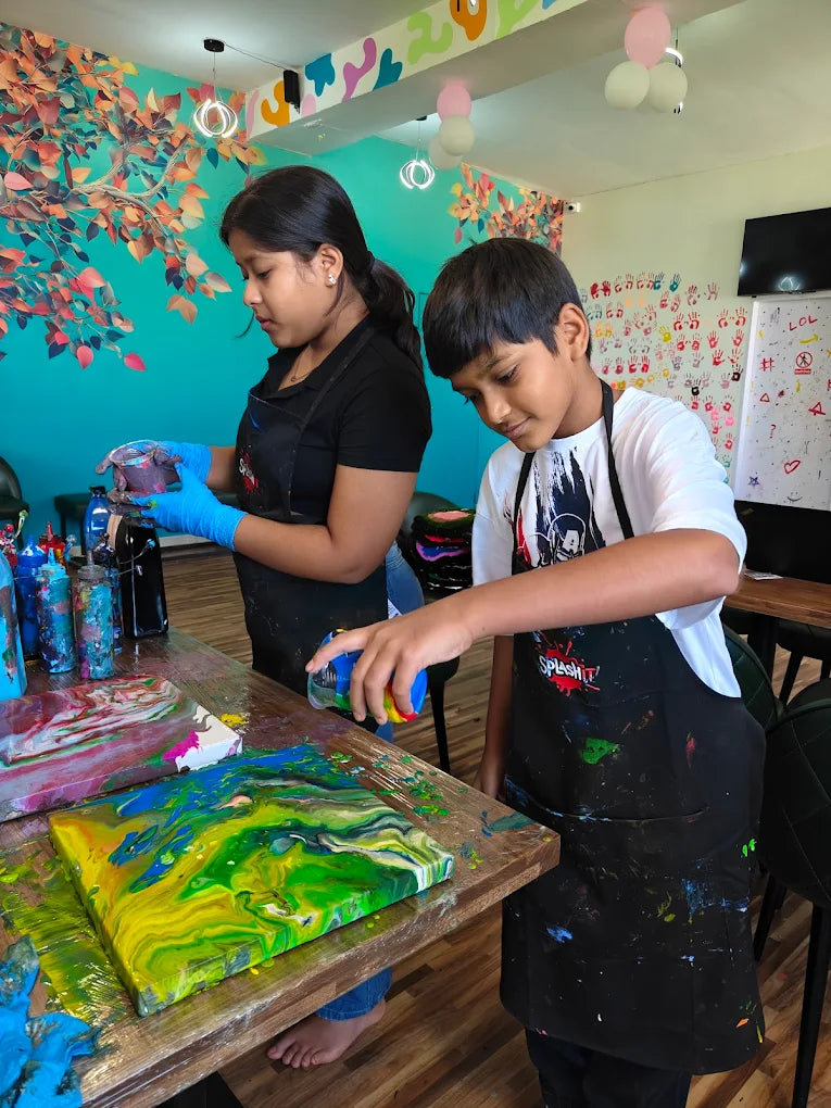Two children are creating abstract art with colorful paints on canvases at a table.