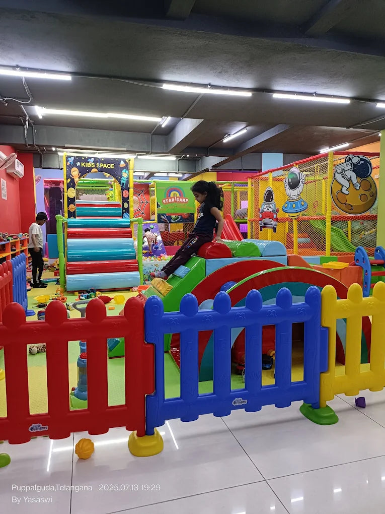 Children play in a colorful indoor playground with slides and climbing structures.