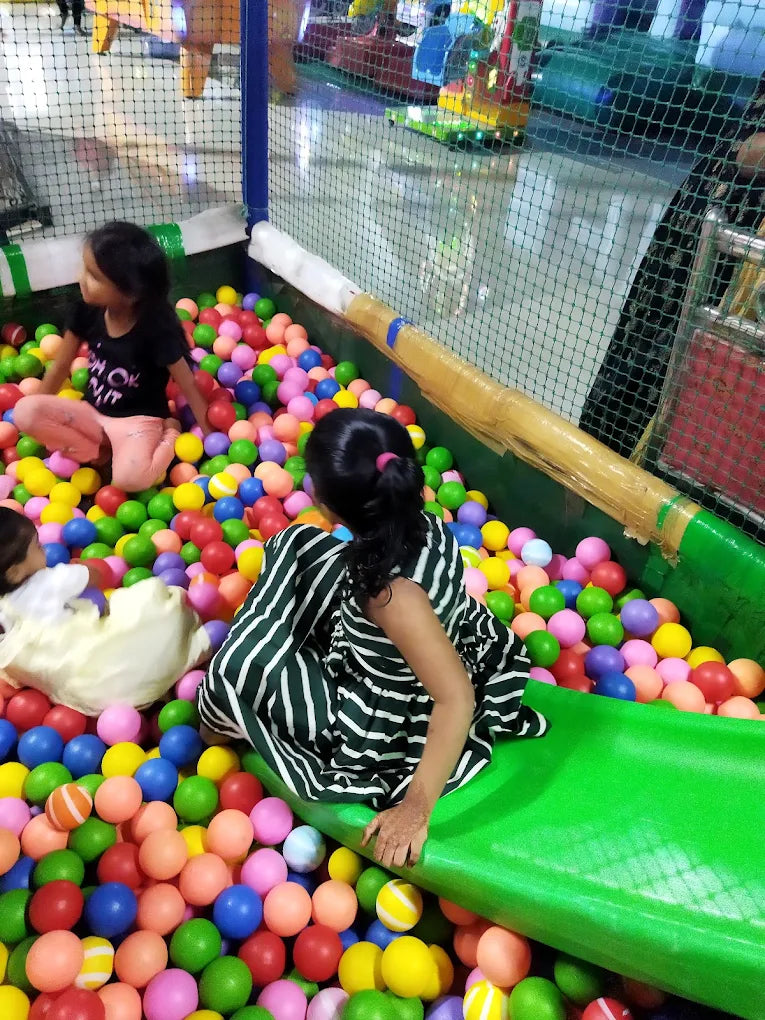 Children play in a ball pit at an indoor playground.