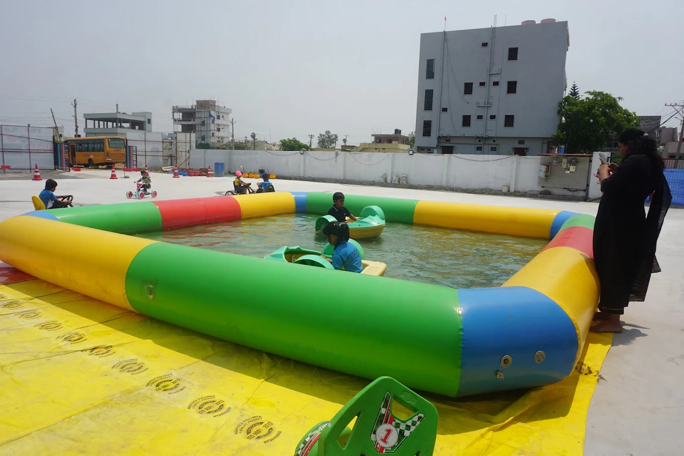 Children enjoy a colorful inflatable pool with paddle boats on a sunny day.