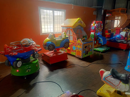 Children's amusement rides, including a plane, car, and train, are set up in a colorful indoor play area.