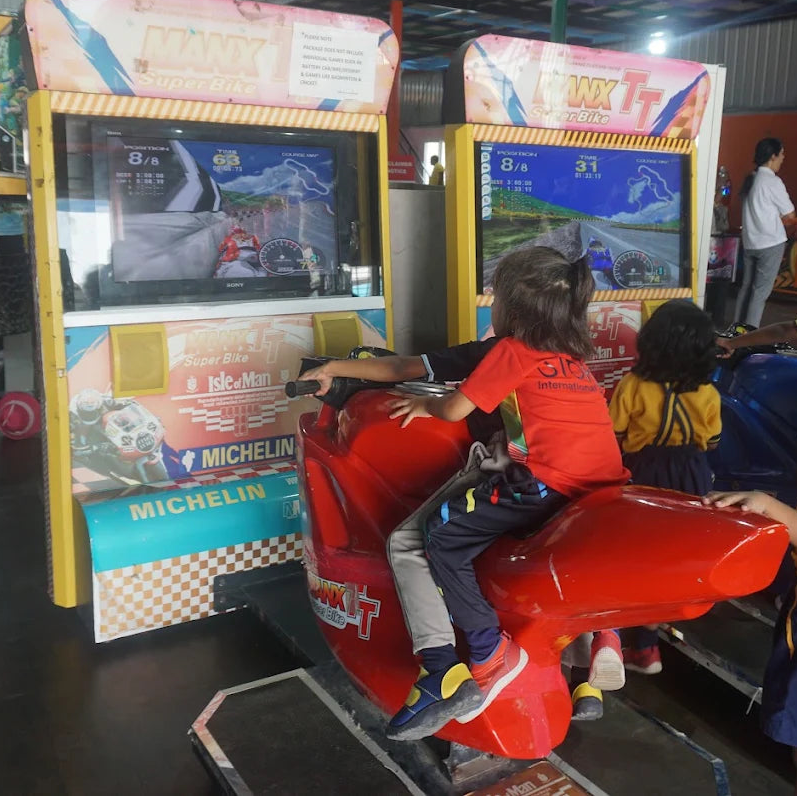 Children play a motorcycle racing arcade game at an amusement center.