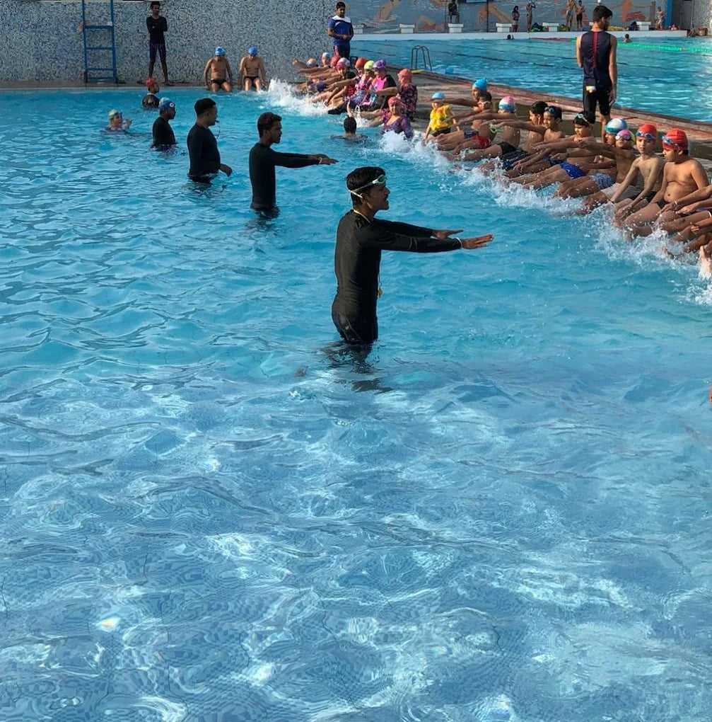Swim instructor teaching a group of swimmers in a pool