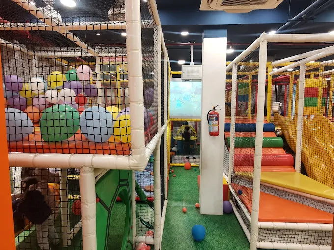 Colorful indoor playground with soft play equipment and safety nets.