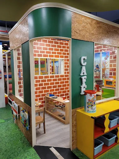 Children's play area with a miniature cafe setup featuring a brick wall and colorful furniture.