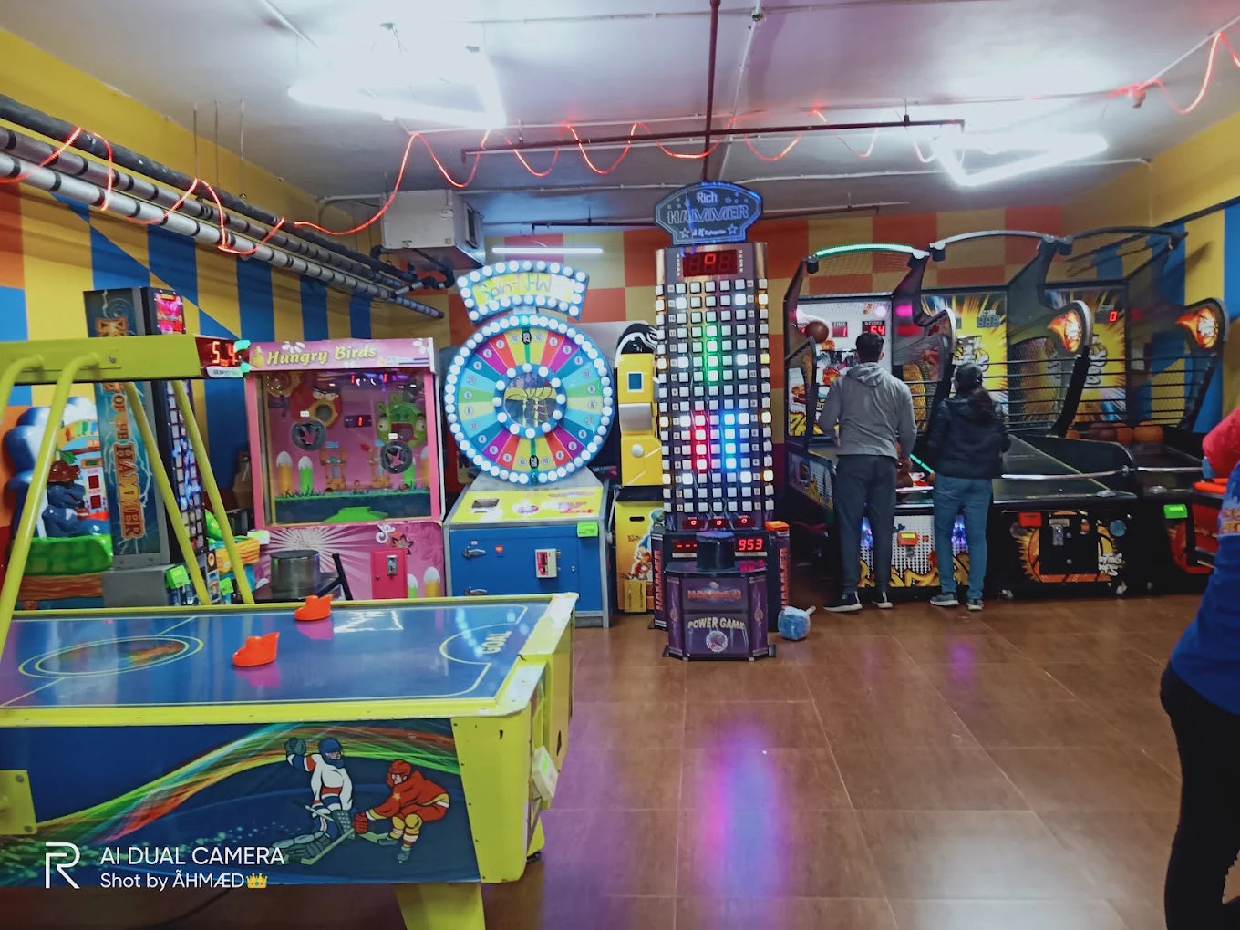 An arcade with various games and people playing.