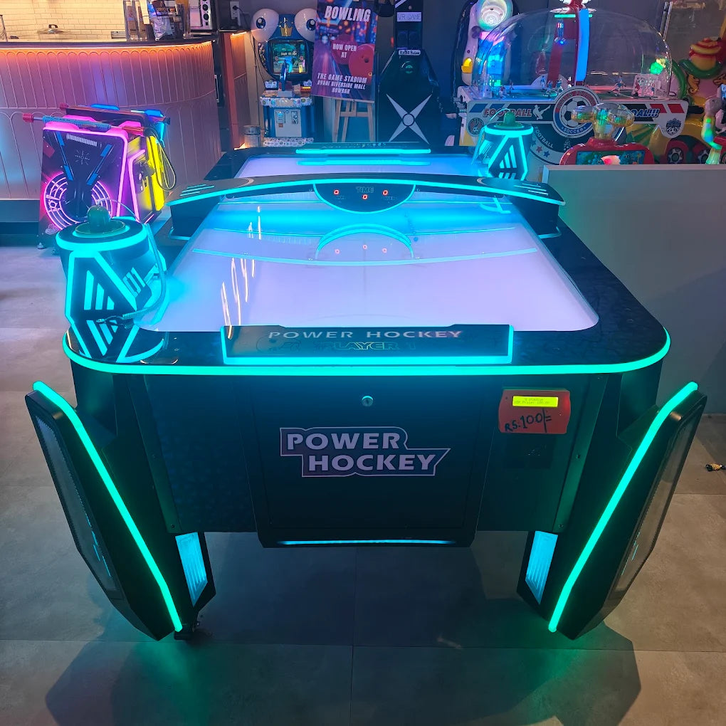 An illuminated air hockey table in an arcade, with neon lights and game machines in the background.