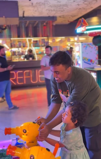 A man and a young child play a carnival game together at an arcade.