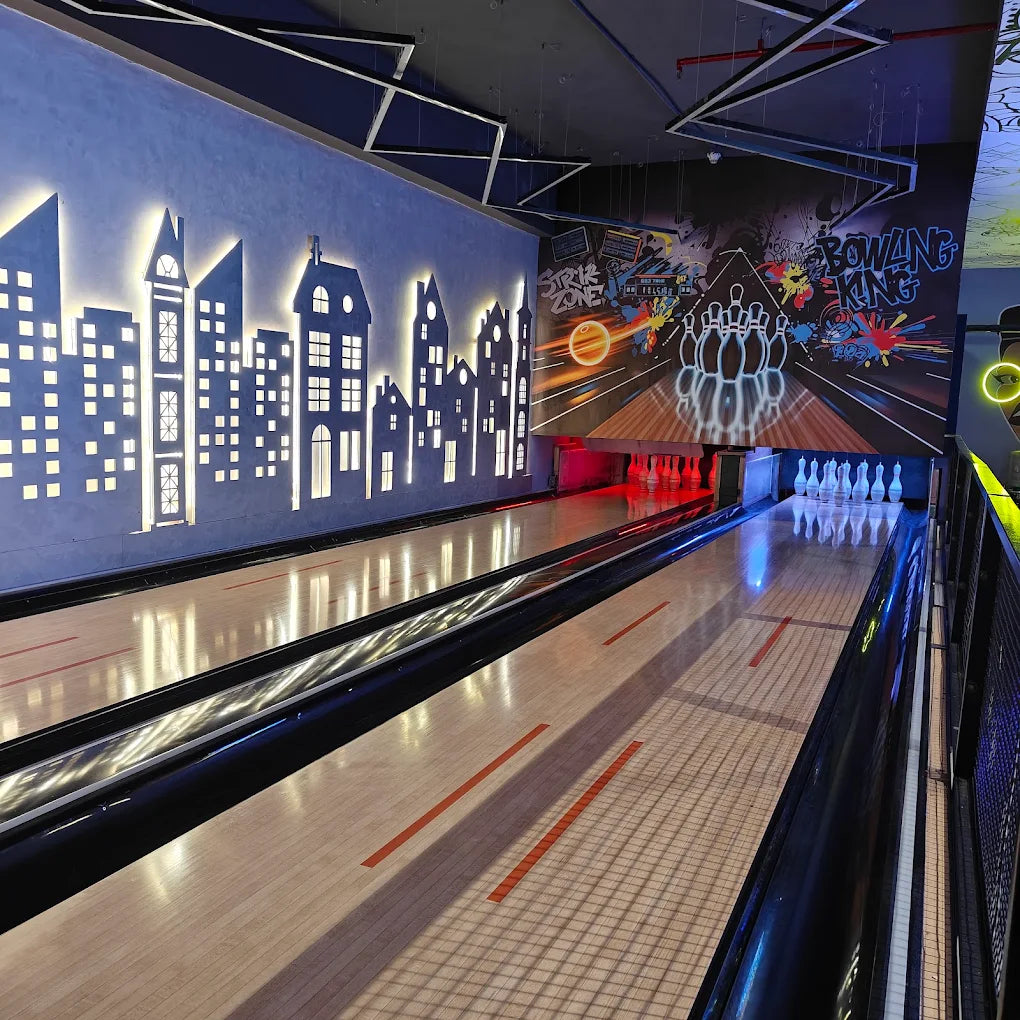 A bowling alley with illuminated city skyline decor and bowling pins.