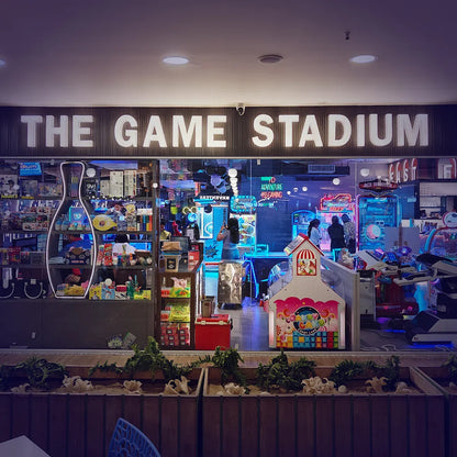 An arcade called "The Game Stadium" with various arcade games and people playing.