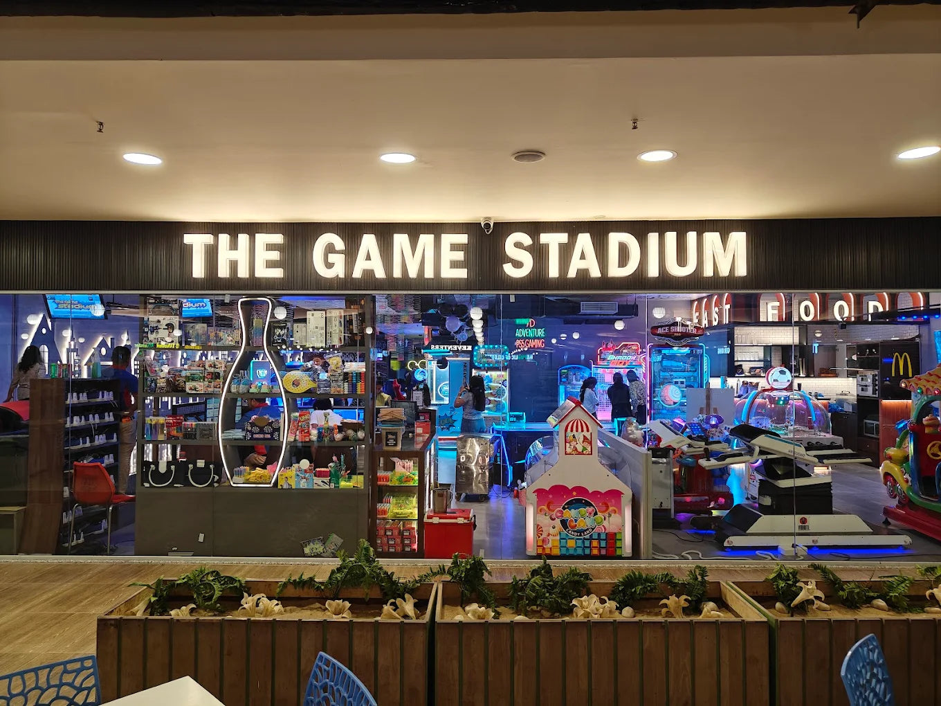 An arcade and game store called "The Game Stadium" with various arcade games and a bowling pin display.