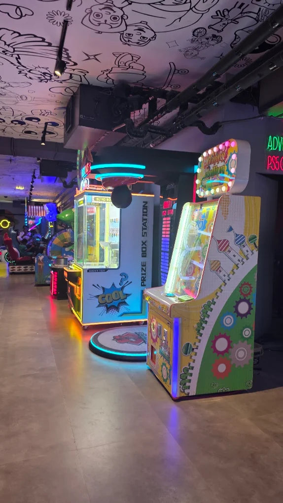 Arcade with colorful prize machines and cartoon drawings on the ceiling.