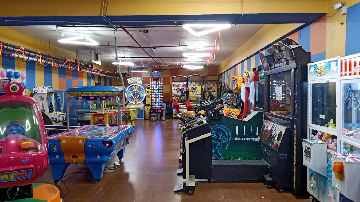 An arcade filled with colorful game machines and an air hockey table.
