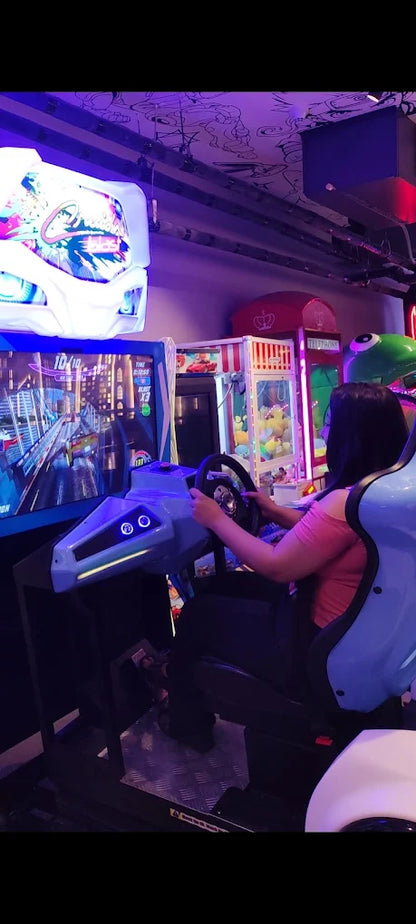 A young woman plays a racing arcade game in an arcade.
