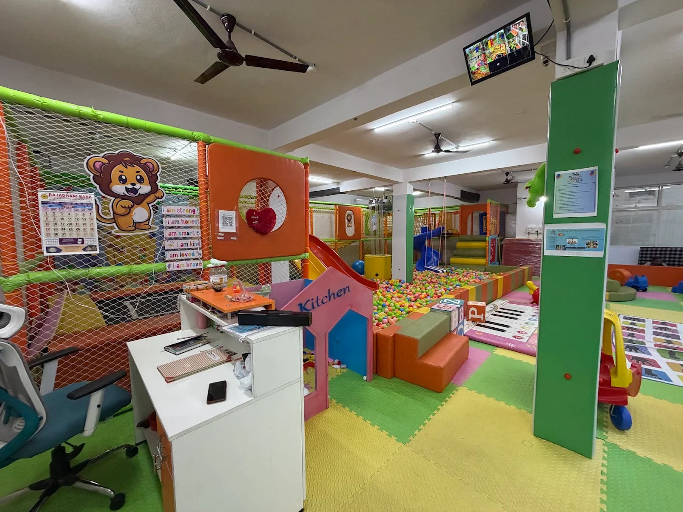 A colorful indoor playground with a ball pit, slides, and soft play structures for children.