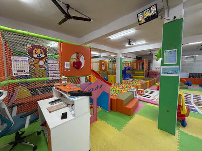 A colorful indoor playground with a ball pit, slides, and soft play structures for children.