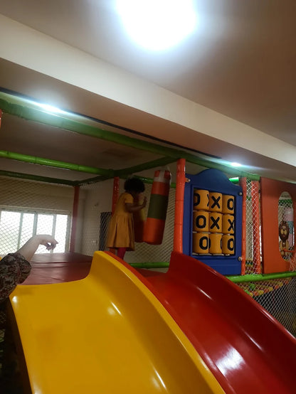 A child plays in a colorful indoor playground with slides and a punching bag.