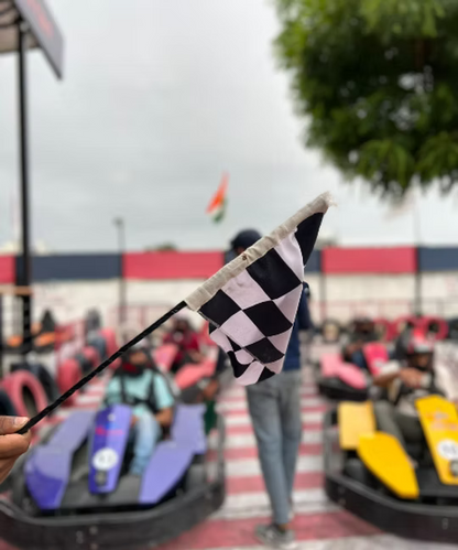 A checkered flag waves at a go-kart race with young adults in the background.