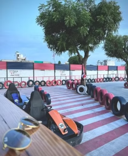 Go-karts lined up on a track with tire barriers, ready for use by adults.