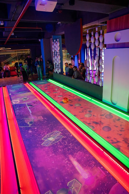 Indoor bowling alley with colorful lanes and people in the background