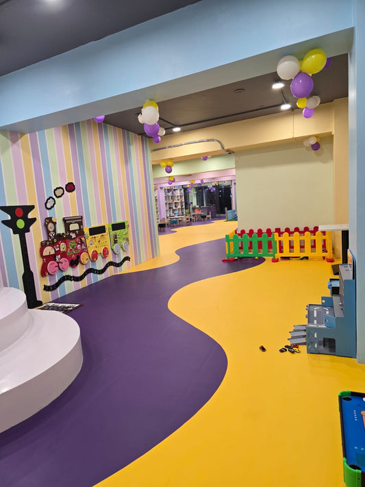 Colorful indoor play area with wavy purple and yellow floor, colorful walls, and toys.