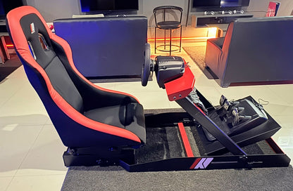 A racing simulator setup with a black and red racing seat, steering wheel, and pedals.