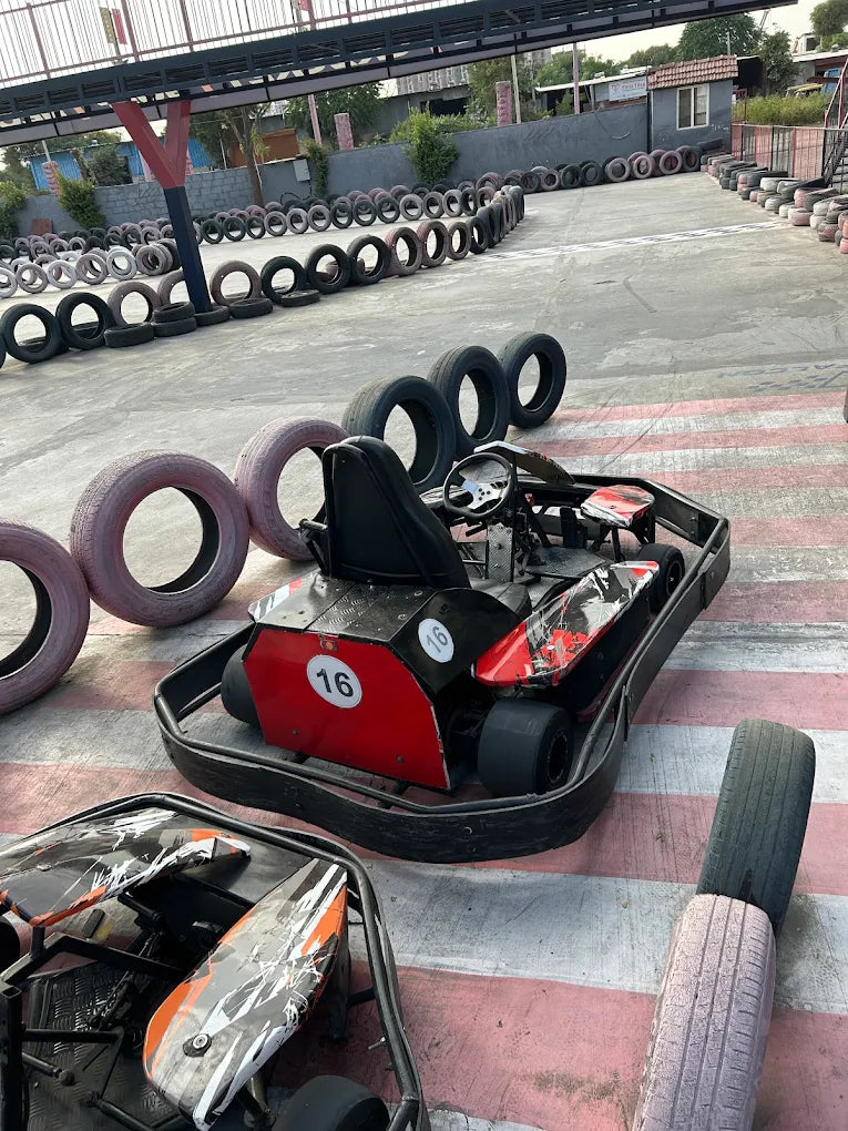 Go-karts are lined up on a track with tire barriers, ready for racing.