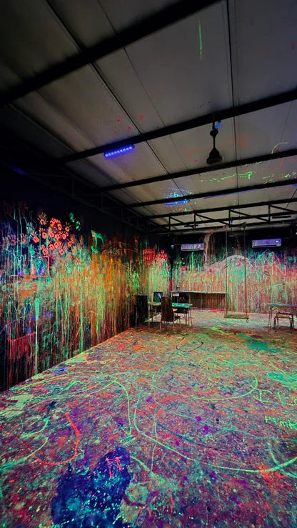 A room covered in neon paint splatters, with handprints on the wall, suggesting a creative art activity.