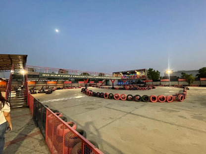 An outdoor go-kart track with tire barriers and a building in the background.