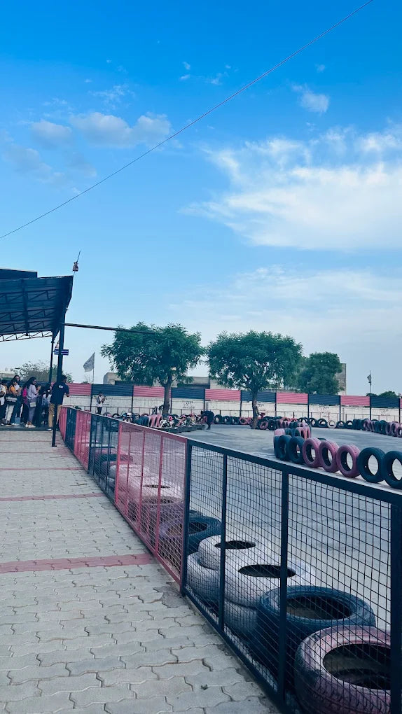 A go-kart track with young people gathered under a shelter, with tires lining the track.