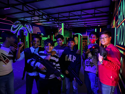 Young boys with laser tag guns in a neon-lit arena.