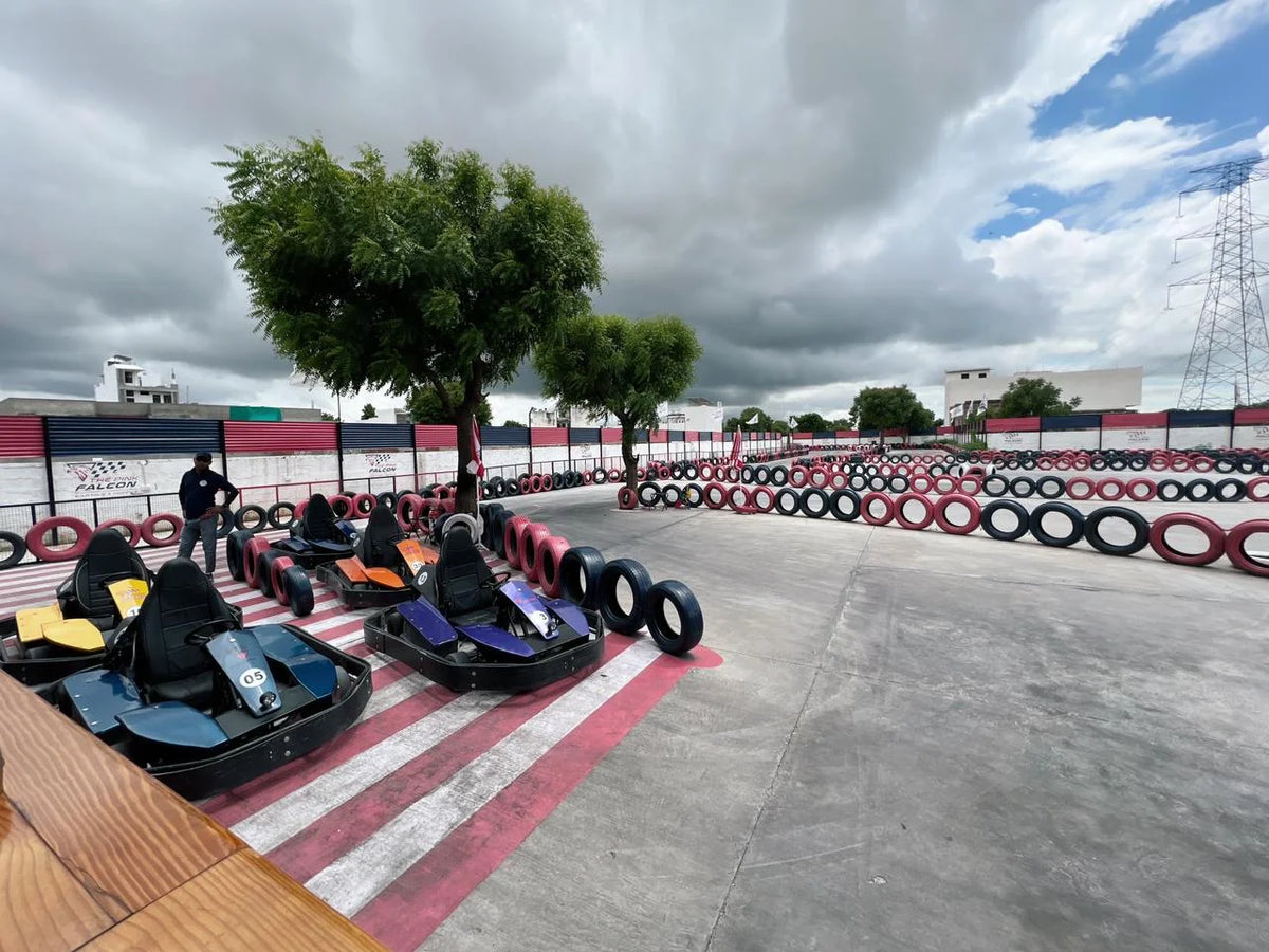 Go-karts lined up on a track with tire barriers and a person standing nearby.