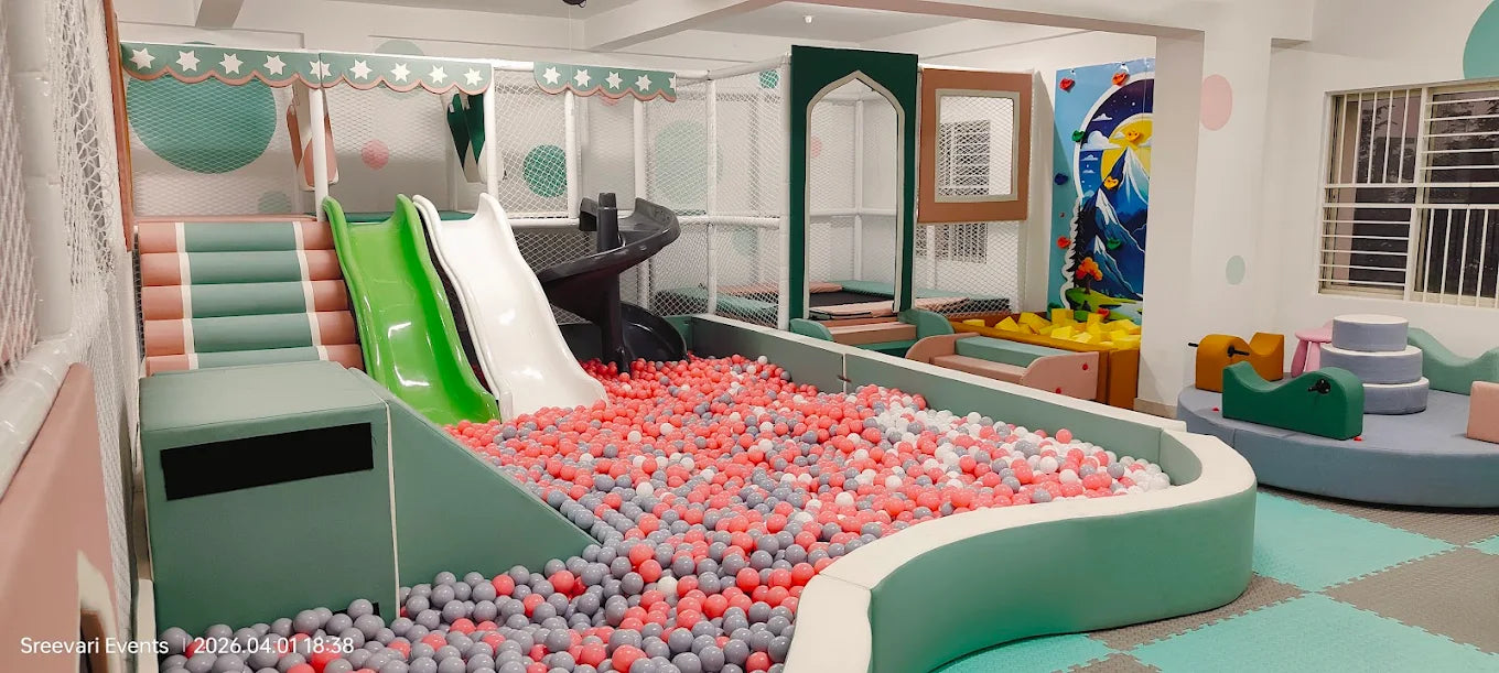 A colorful indoor playground with slides, a ball pit, and soft play structures for children.