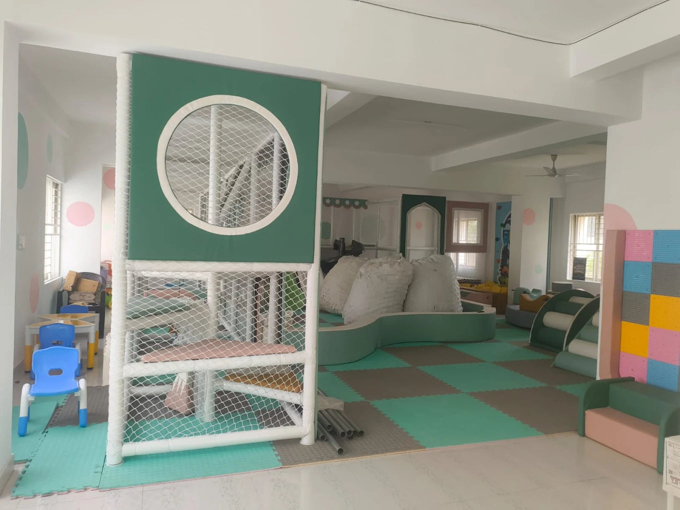 A colorful indoor play area for young children with soft play structures and seating.