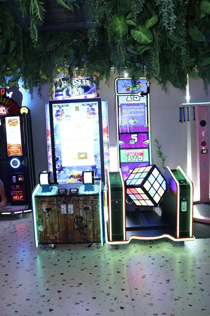 Illuminated arcade games including a puzzle challenge with glowing cube and interactive controls in a vibrant indoor zone