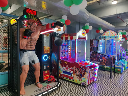 Indoor arcade zone featuring colorful game machines and a boxing punching strength tester with vibrant lighting and decorations