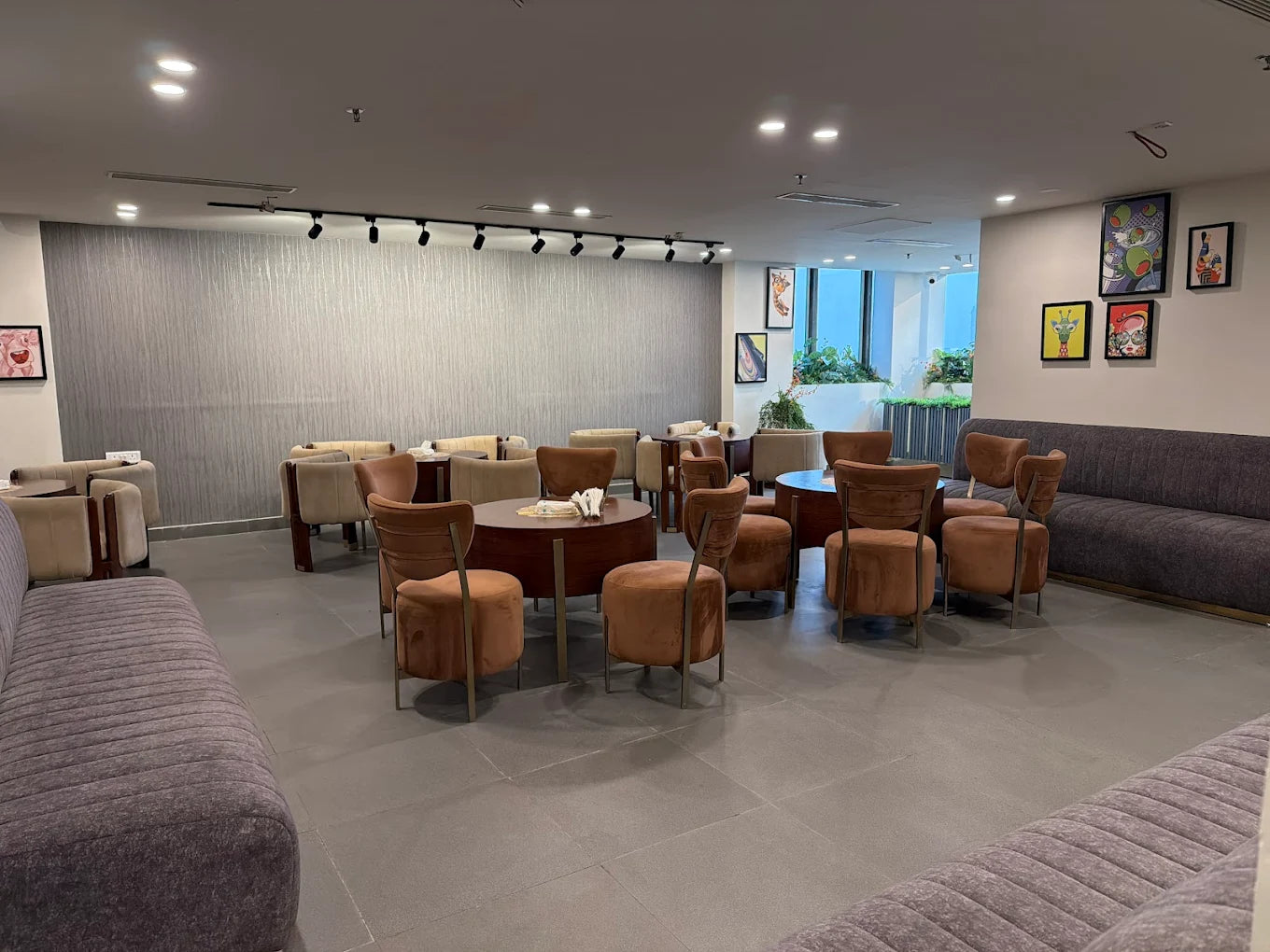 Spacious indoor lounge area with cushioned chairs, round tables, and modern artwork on walls in a play zone setting