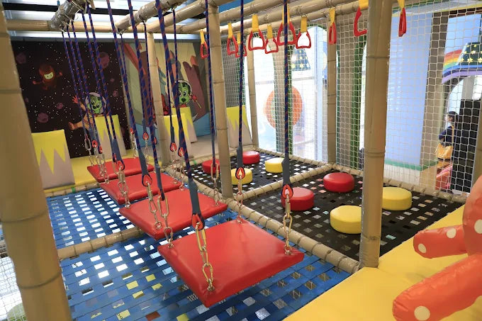 Children's indoor play area with swings and colorful flooring