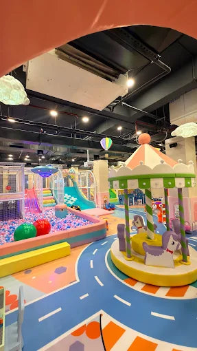 Bright indoor play zone with carousel, ball pit, colorful slides, and playful decorations for children.