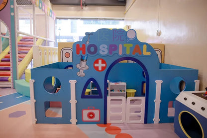 Blue and white playhouse designed as a colorful hospital with toy medical equipment in children’s indoor play center